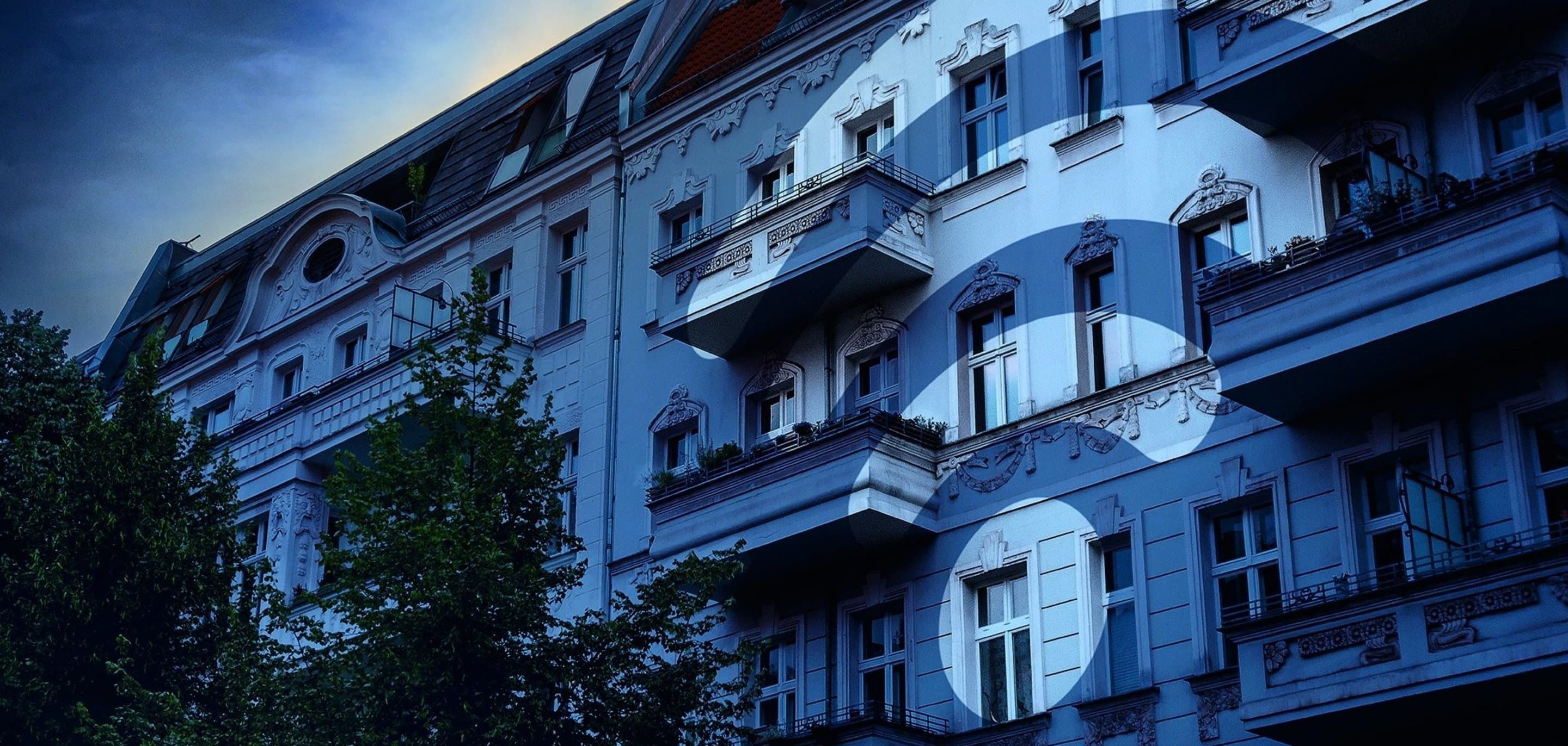 Häuserfront über die ein blauer Filter und ein WLAN-Icon gelegt ist.
