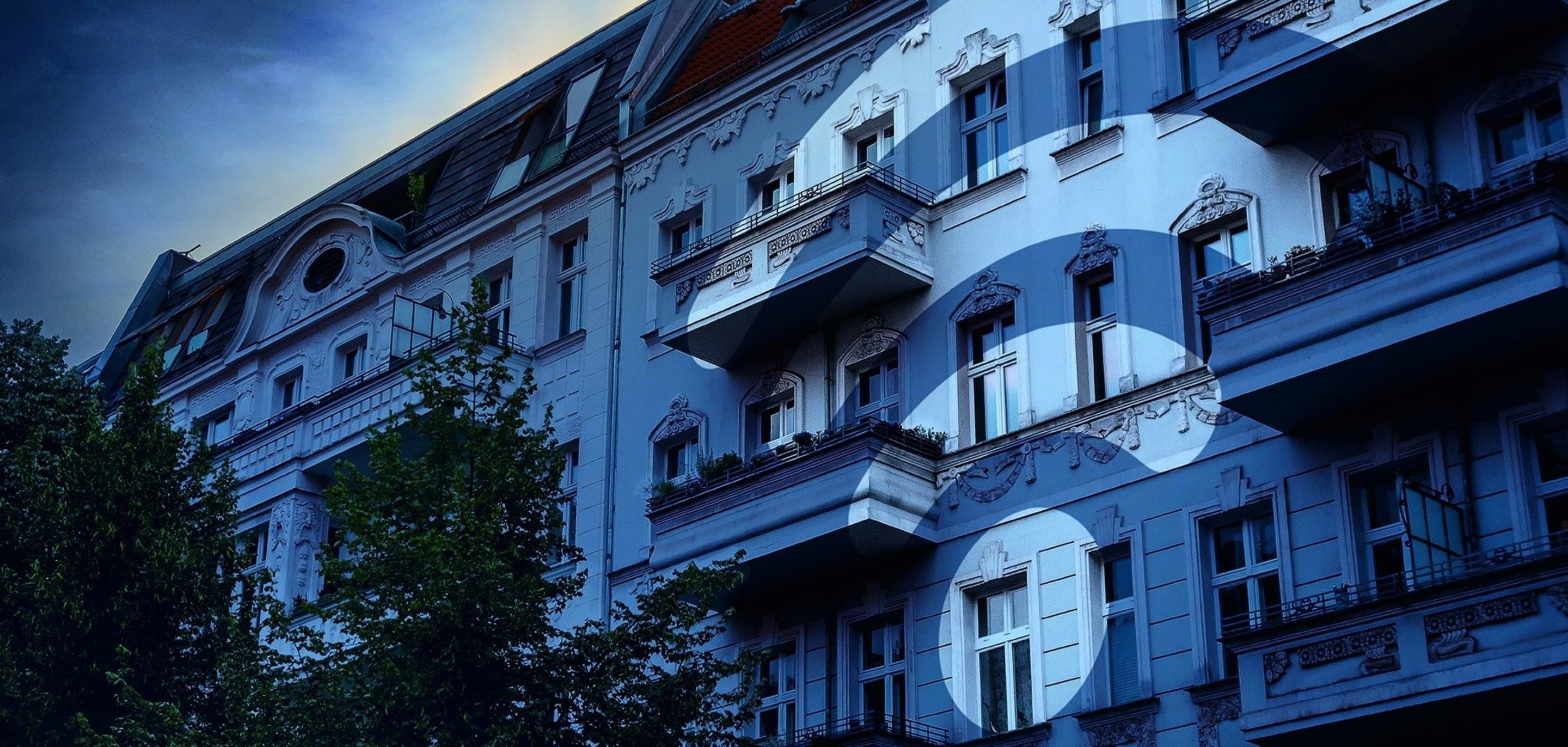 Häuserfront über die ein blauer Filter und ein WLAN-Icon gelegt ist.