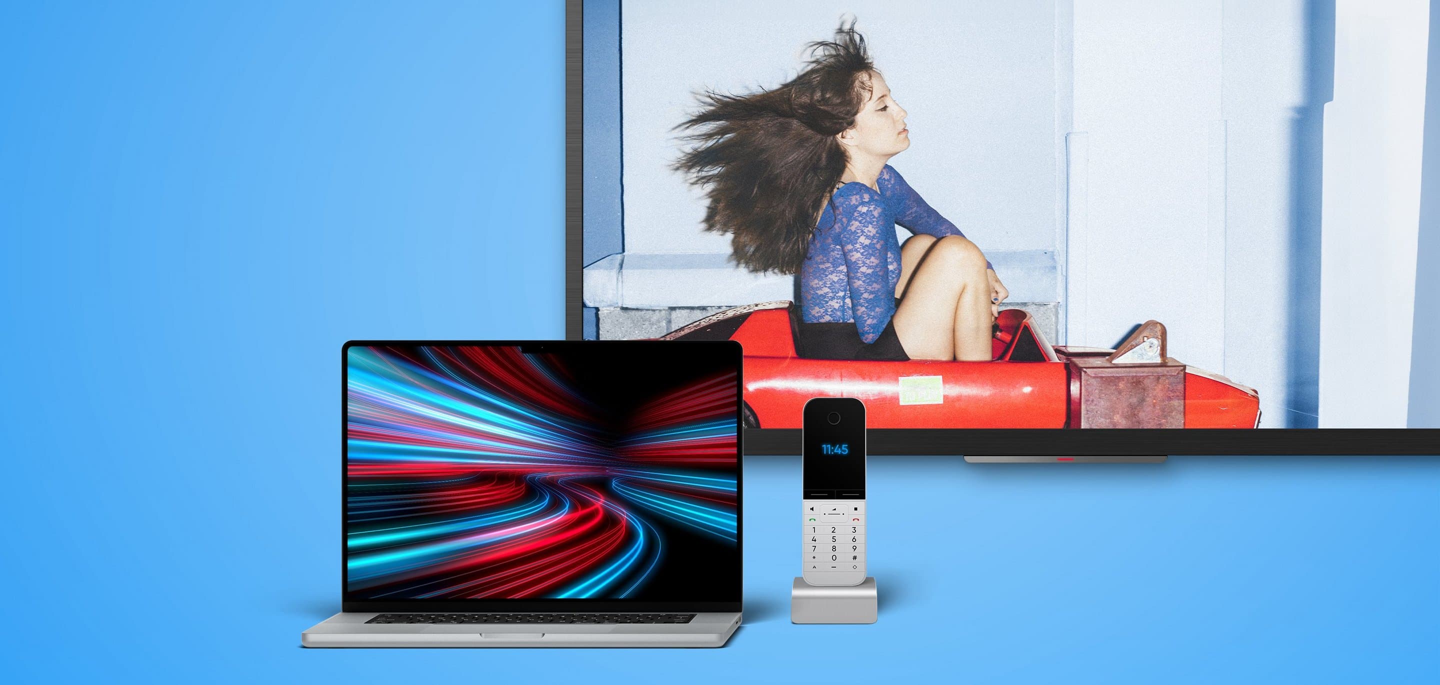 NetCologne Kombi Tarif: Internet, Telefon und TV Laptop mit Lichtspur-Display, daneben ein Telefon und im Hintergrund ein Bildschirm mit einer Person in einem roten Fahrgeschäft.