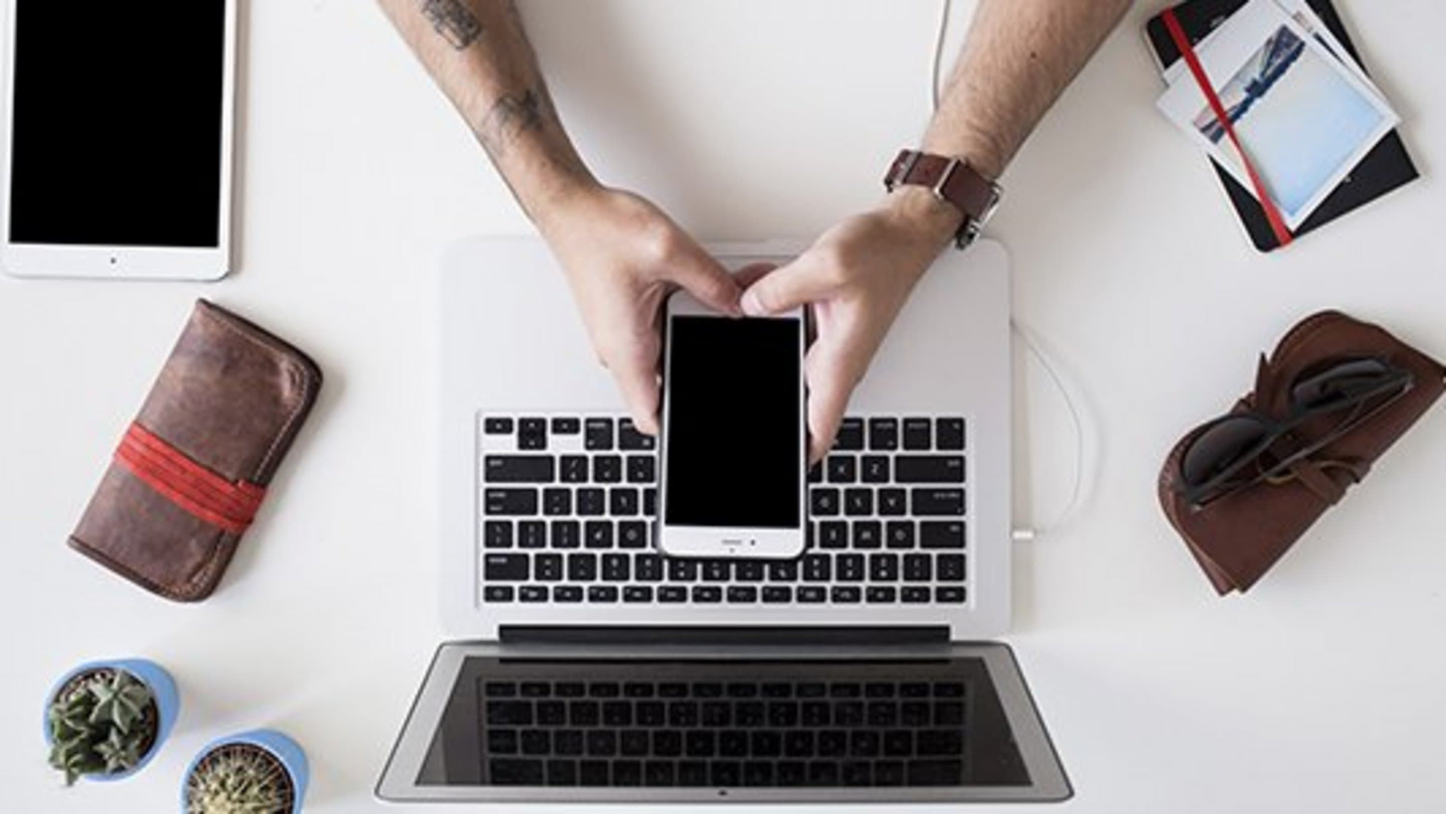 Aufnahme eines Laptops und Handys von oben, die auf einem Tisch platziert sind.