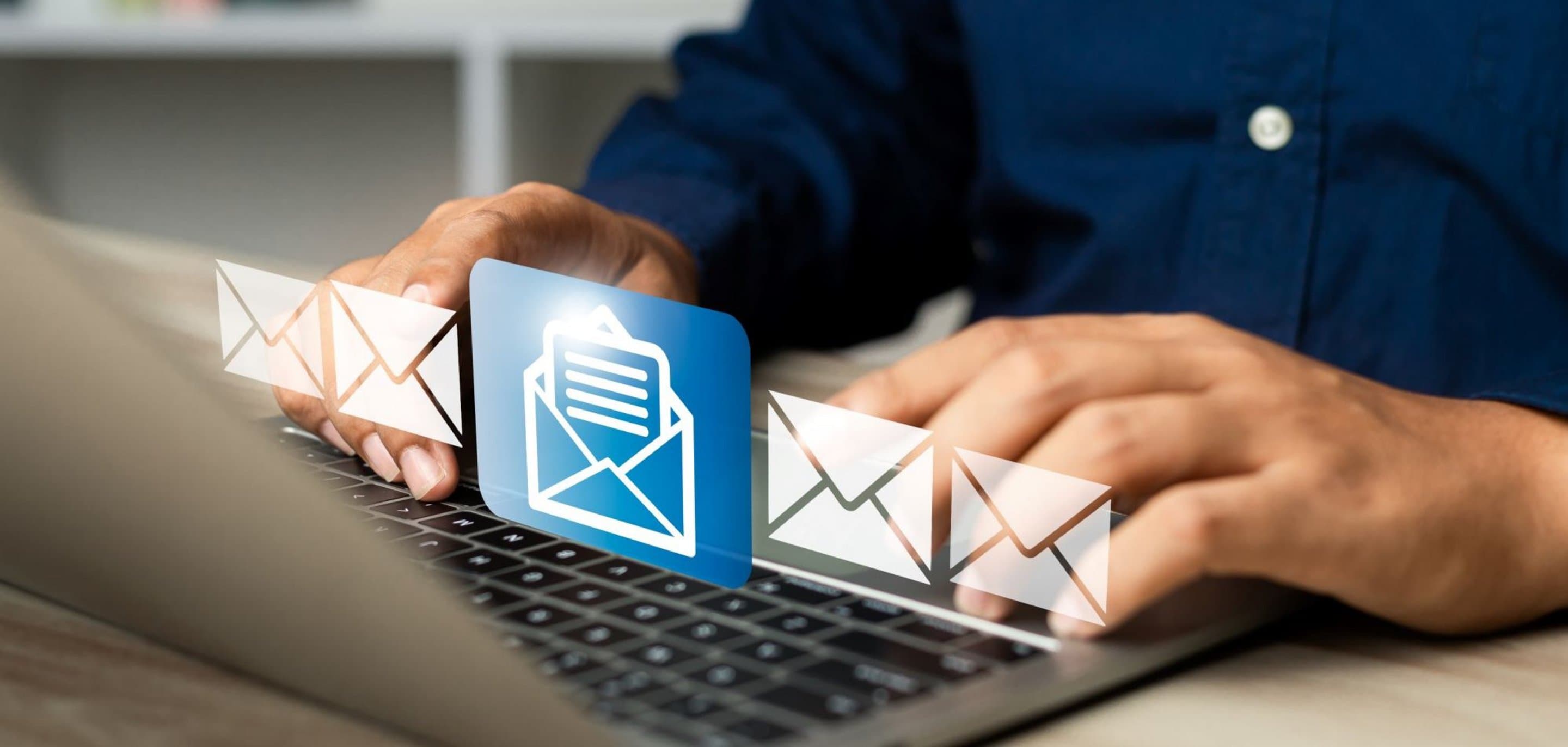 Nahaufnahme von Händen auf einer Laptop-Tastatur mit eingeblendeten E-Mail-Symbolen in Weiß und Blau.