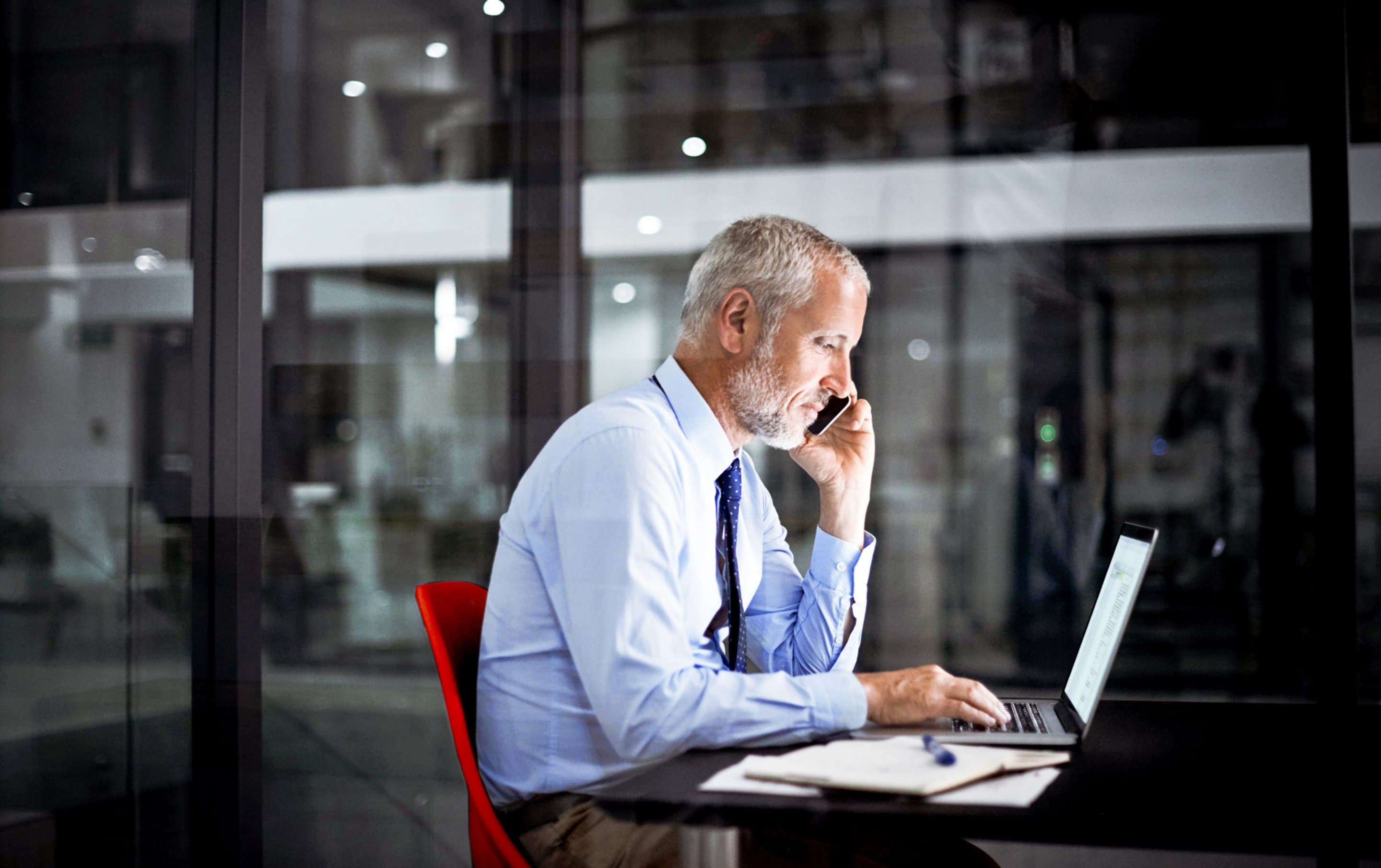 Mann am Laptop arbeitet und telefoniert. Mann am Laptop arbeitet und telefoniert.