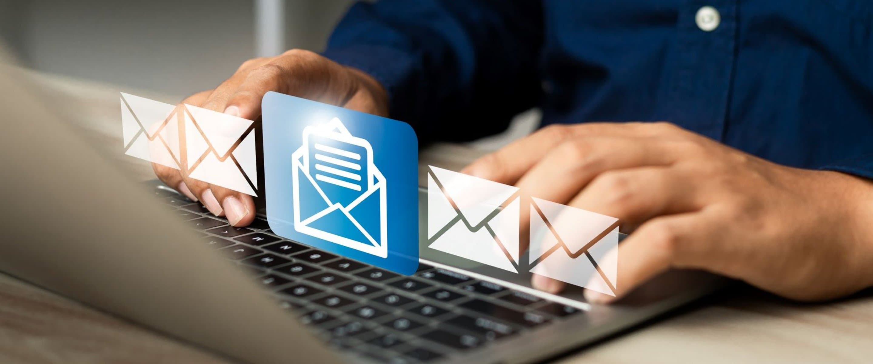 Nahaufnahme von Händen auf einer Laptop-Tastatur mit eingeblendeten E-Mail-Symbolen in Weiß und Blau.